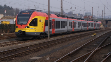 Triebwagen der Hessischen Landesbahn mit gelb-roter Front im Gleisvorfeld des Siegener Hauptbahnhofes, die Zugzielanzeige lautet "Frankfurt Hbf"